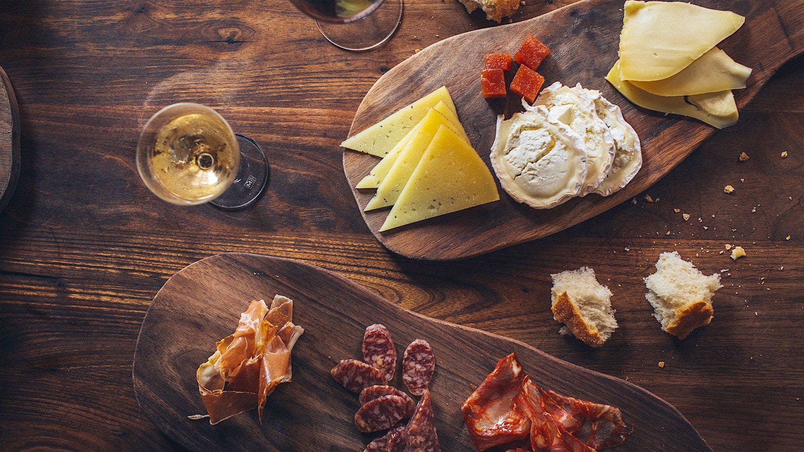 A plate of charcuterie and a plate of cheese next to a glass of wine at Barcelona Wine Bar